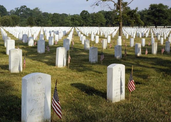 a grave, placing flowers and flags in remembrance on Memorial Day.